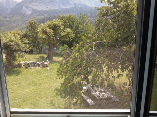 a window with a view of a park with trees and benches at Ferme Racine in Jausiers