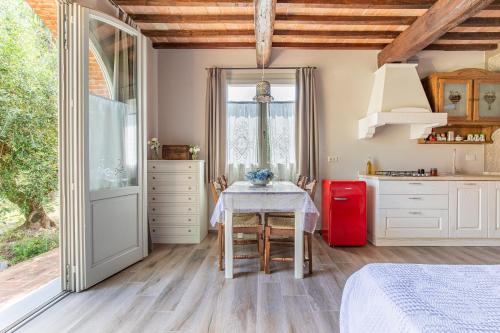 a kitchen with a table and a kitchen with white cabinets at Fienile Olivo, art of living Tuscany in Torre