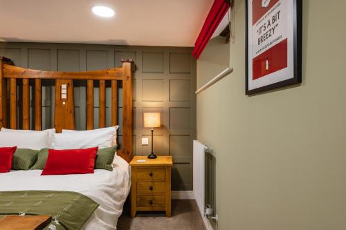 a bedroom with a wooden bed with red pillows at Spacious, luxury town centre Granary conversion in Stamford