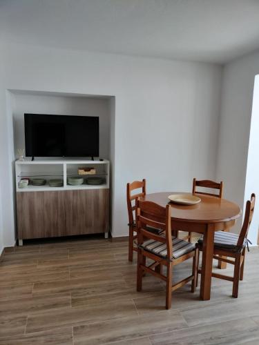 a dining room with a table and chairs and a tv at Casa Baptista in Vila do Bispo
