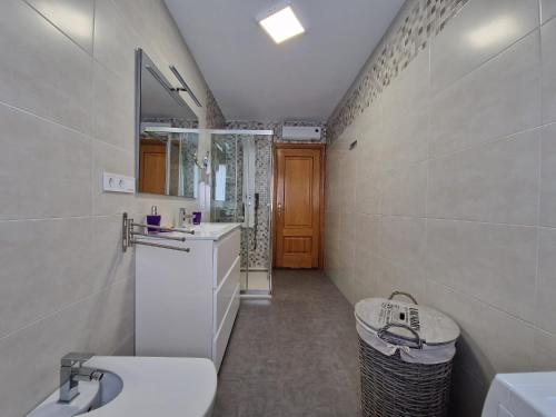 ein Badezimmer mit einem Waschbecken, einem WC und einem Spiegel in der Unterkunft Acogedor alojamiento en Sanxenxo in Sanxenxo