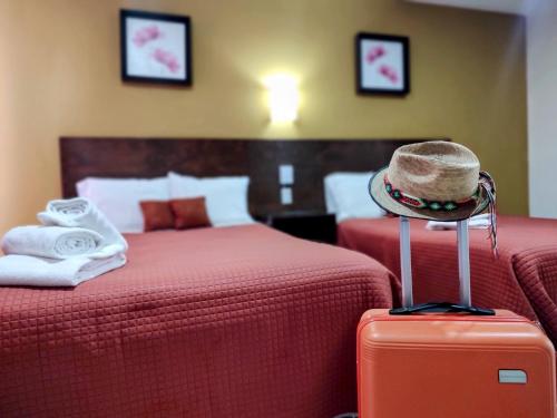 a hotel room with two beds and a hat on a suitcase at Posada Del Carmen Aguascalientes in Aguascalientes