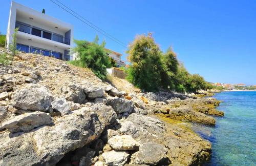 a building on a rocky shore next to the water at Lovely apartment Vila Zala in Kali