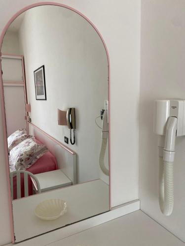 a mirror in a room with a bed and a phone at Hotel Rosy in Rimini