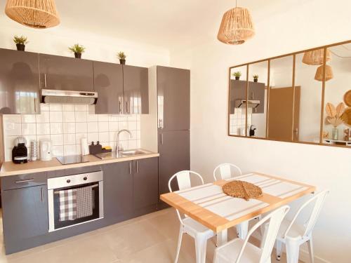 uma cozinha com mesa e cadeiras e uma cozinha com lavatório em Buena Vista Appartement en bord de mer em Argelès-sur-Mer