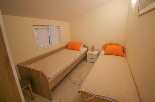 2 Betten in einem kleinen Zimmer mit orangefarbenen Kissen in der Unterkunft Goga Apartment in Kotor