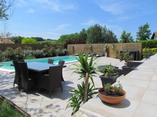 un patio avec une table et des chaises à côté d'une piscine dans l'établissement SCI LOUXOR BY DOMINIQUE, à Urrugne