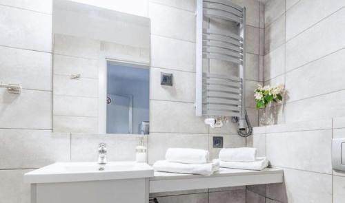 W białej łazience znajduje się umywalka i lustro. w obiekcie Guest Apartments Orłowo w mieście Gdynia