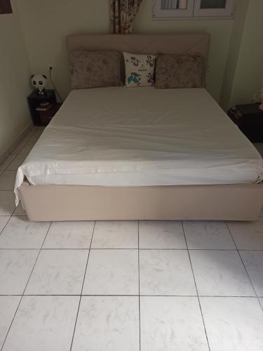 a bed in a bedroom with a tiled floor at Christos beach apart in Kos Town