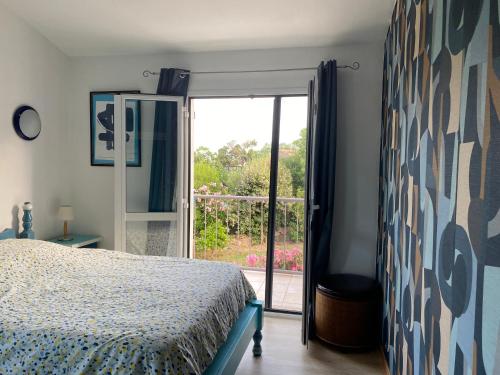 une chambre avec un lit et une porte coulissante en verre dans l'établissement VILLA LARGIA porto vecchio - A 5 MIN DES PLAGES DE PALOMBAGGIA - CALME- CLIMATISATION, à Porto-Vecchio