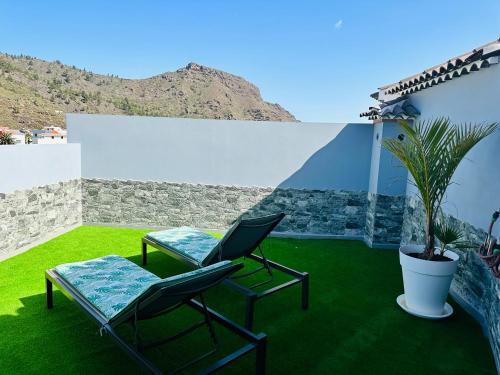 two chairs and a table on a patio with grass at amplio duplex in Tamaimo