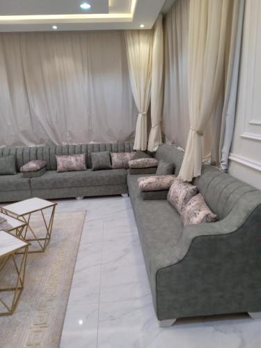 ein Wohnzimmer mit Sofas, Tischen und Vorhängen in der Unterkunft شاليه لوسيل in Chamis Muschait