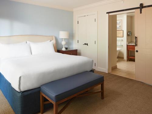 a bedroom with a white bed and a blue stool at Boar's Head Resort in Charlottesville
