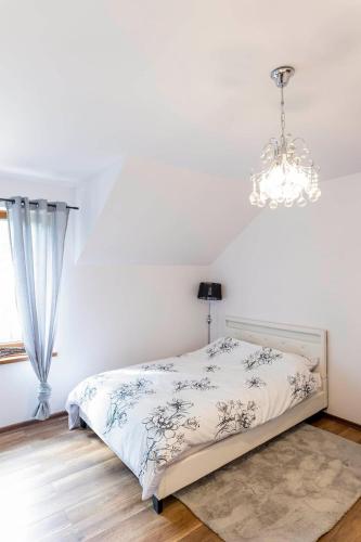 a white bedroom with a bed and a chandelier at Agroturystyka Głuchowskie Specjały in Głuchów