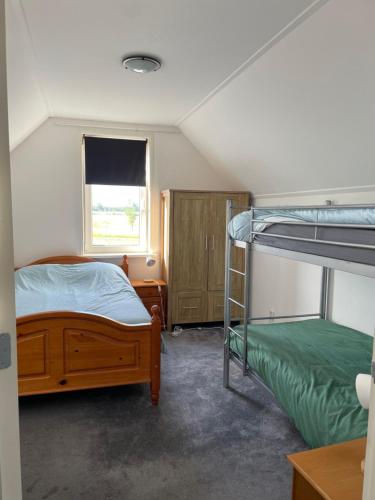 1 Schlafzimmer mit 2 Etagenbetten und einem Fenster in der Unterkunft Heerlijk hoek appartement net buiten het dorp 