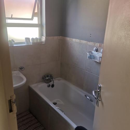 a bathroom with a bath tub and a sink at Pablo and Sons Apartments in Polokwane