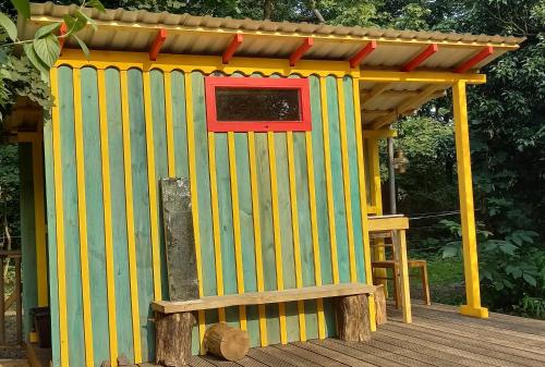 een geel en rood bijgebouw op een houten terras bij Einfachlosmachen-Zeltpunkt 