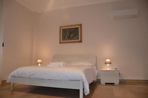 1 dormitorio con 1 cama blanca y 2 mesitas de noche en RESIDENZA LE TERRAZZE SASSARI CASA G PISCHEDDA bY FANTASTIC SARDINIA, en Sassari