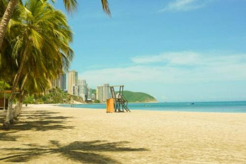 a playground on a beach with palm trees and the ocean at Hostel Santa Marta el Rodadero in Santa Marta