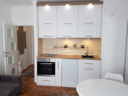 a white kitchen with white cabinets and a table at Emili apartment in Belgrade