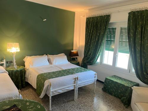 a green bedroom with two beds and a window at Eveline Portosole Hotel in Sanremo