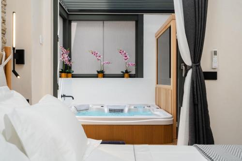 La salle de bains est pourvue d'une baignoire avec des fleurs dans la fenêtre. dans l'établissement Legato Spa Suites, à Naxos Chora