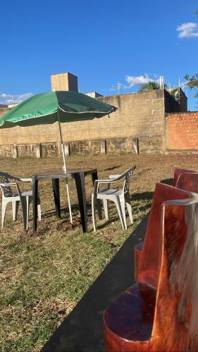 mesa de picnic con sombrilla verde y sillas en CASA DE TEMPORADA DA MEiRE, en Carolina