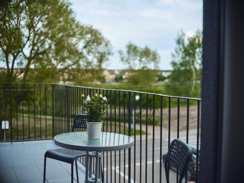 a table with chairs and a vase of flowers on a balcony at LOFT ROOMS ŁEBA in Łeba