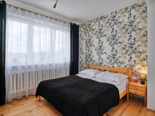 sypialnia z łóżkiem i dużym oknem w obiekcie LOFT ROOMS ŁEBA w Łebie