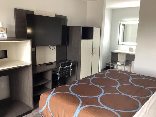 a hotel room with a bed and a television at Super 8 by Wyndham Baltimore Northwest in Baltimore