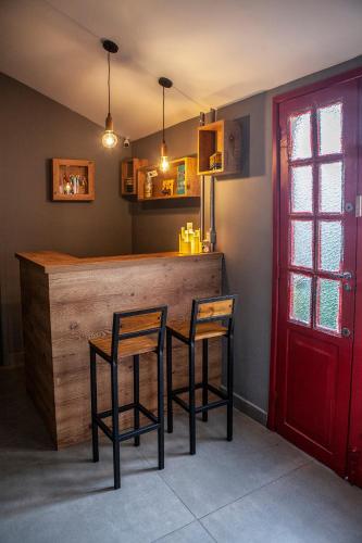 a kitchen with a bar with two chairs and a red door at Lobie Armazém São Joaquim in Rio de Janeiro