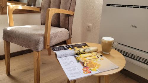 a table with a chair and a book and a cup of coffee at B&B Plitvica Villa Prica in Plitvička Jezera
