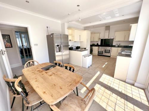 a kitchen with a wooden table and chairs at Four Bedroom Family Abode with Hot Tub, Garden and BBQ in Bournemouth