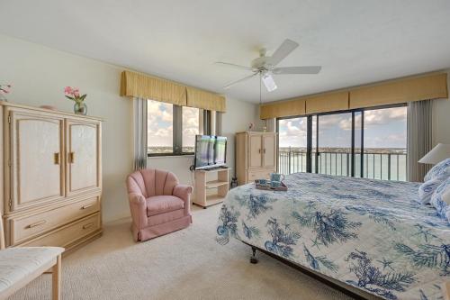 a bedroom with a bed and a tv and a chair at Marco Island Condo with Ocean Views and Resort Perks! in Marco Island