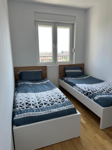 two beds in a room with two windows at Skyline Apartment 1 in Peje