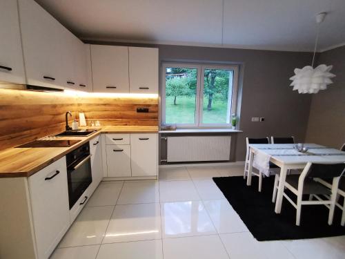 a kitchen with white cabinets and a table and a window at Apartamenty Kotarz Sauna&Relaks in Brenna