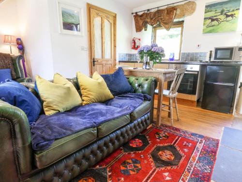 a leather couch in a living room with a kitchen at Daffodil Cottage in Danby