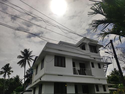 een wit gebouw met palmbomen op de achtergrond bij Micro homestay mulavukad in Ernakulam