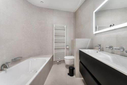 a white bathroom with a tub and a toilet at Zonnig Luxueuze Appartementen La Coronne in Knokke-Heist