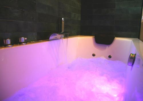 a pink bath tub filled with lots of pink water at L'Eden Chic - Balneo - Jardin - Parking gratuit in Arras