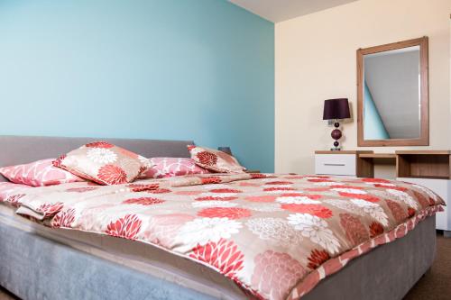a bed with a red and white comforter and a mirror at Dom Gościnny Liść Dębu in Karnieszewice