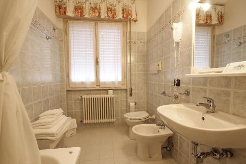 bagno bianco con lavandino e servizi igienici di Hotel Miramare a Forte dei Marmi