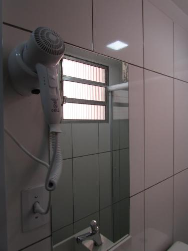 um secador de cabelo na casa de banho com espelho em Hotel Salomão - Próximo a 25 de Março, Bom Retiro, Brás e Rua Santa Efigênia, a 2 minutos do Mirante Sampa Sky e pista de Skate Anhangabaú em São Paulo