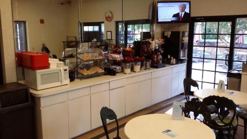 a restaurant with a counter with a microwave and tables at Ramada by Wyndham Temple Terrace/Tampa North in Tampa