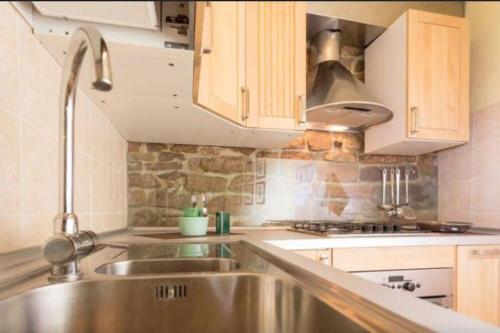 uma cozinha com um lavatório de aço inoxidável e armários de madeira em Lovely apartment in the heart of Perugia em Perugia