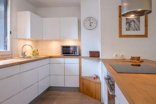 une cuisine avec des placards blancs et une horloge murale dans l'établissement T3 with breathtaking views of Mont Blanc, à Chamonix-Mont-Blanc