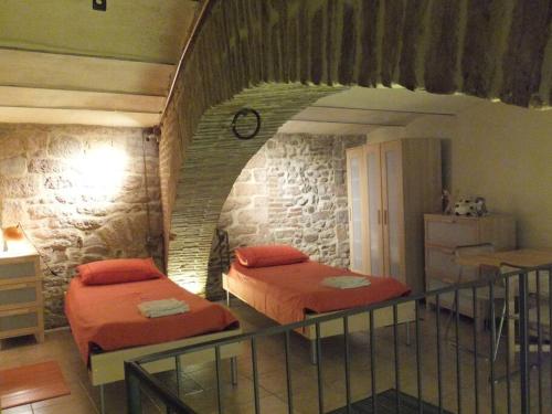 two beds in a room with a stone wall at Lovely apartment in the heart of Perugia in Perugia