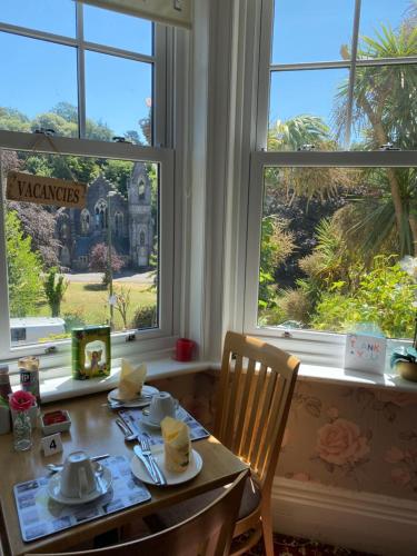 a dining room with a table and two windows at The Palms Guest house in Torquay