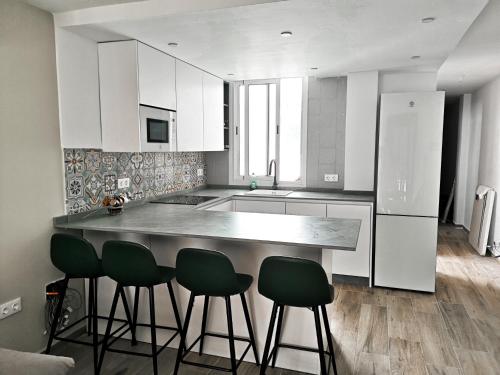 Apartamento a 1 MINUTO de la playa en GARRUCHA في غاروشا: مطبخ مع خزائن بيضاء وكراسي بار خضراء