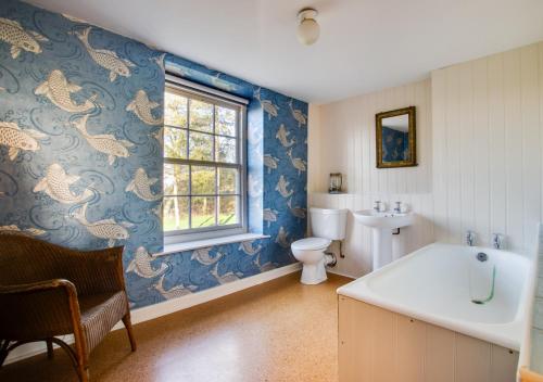 ein Bad mit einem Waschbecken, einem WC und einem Fenster in der Unterkunft Three Ash Farm in Bungay